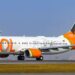 Aeronave Boeing 737 da GOL Linhas Aéreas taxiando em uma pista de aeroporto sob o sol. O avião possui a fuselagem branca com o logotipo laranja e uma pintura especial na cauda celebrando 150 anos com a imagem de Santos Dumont.