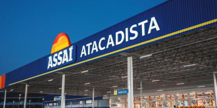 Fachada externa de uma unidade do Assaí Atacadista com letreiro azul e amarelo em destaque sob um céu azul.