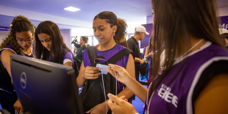 Jovens com camisetas roxas do CIEE recebem orientação durante mutirão de estágio e aprendizagem em ambiente interno.