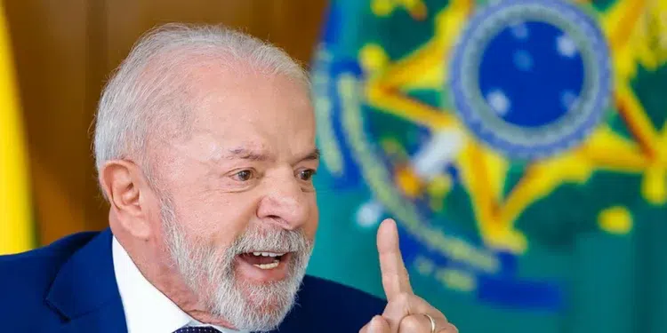 Presidente Lula gesticula com dedo indicador erguido durante entrevista no Palácio do Planalto, com bandeira do Brasil ao fundo.