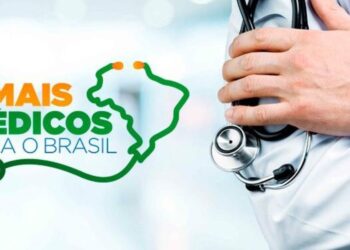 Foto em close de uma mão profissional de saúde segurando um estetoscópio de metal. À esquerda, a logo oficial do programa nas cores verde e laranja com o texto: "MAIS MÉDICOS PARA O BRASIL", ao lado de um contorno do mapa do Brasil formado pelo fio de um estetoscópio. Fundo claro e desfocado de ambiente hospitalar.