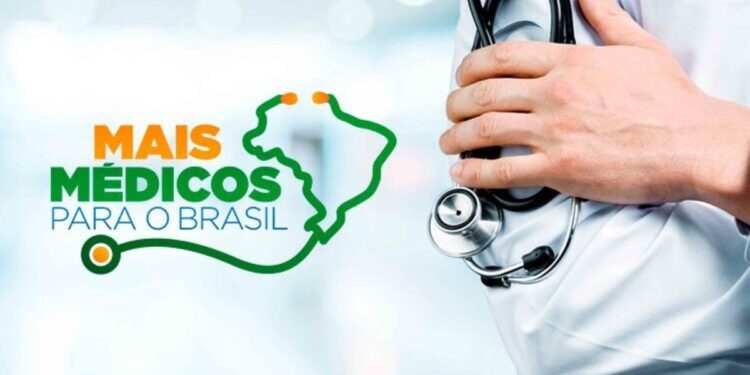 Foto em close de uma mão profissional de saúde segurando um estetoscópio de metal. À esquerda, a logo oficial do programa nas cores verde e laranja com o texto: "MAIS MÉDICOS PARA O BRASIL", ao lado de um contorno do mapa do Brasil formado pelo fio de um estetoscópio. Fundo claro e desfocado de ambiente hospitalar.