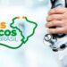 Foto em close de uma mão profissional de saúde segurando um estetoscópio de metal. À esquerda, a logo oficial do programa nas cores verde e laranja com o texto: "MAIS MÉDICOS PARA O BRASIL", ao lado de um contorno do mapa do Brasil formado pelo fio de um estetoscópio. Fundo claro e desfocado de ambiente hospitalar.