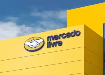 Prédio amarelo do Mercado Livre com logotipo de mãos apertadas e céu azul ao fundo